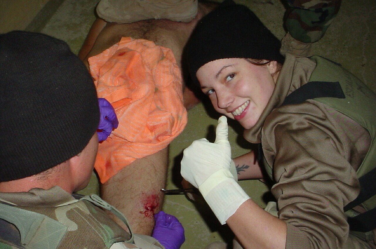 Příslušnice americké armády pózuje u zraněného vězně v Abú Ghraib. (foto: Profimedia) profimedia 0601242271